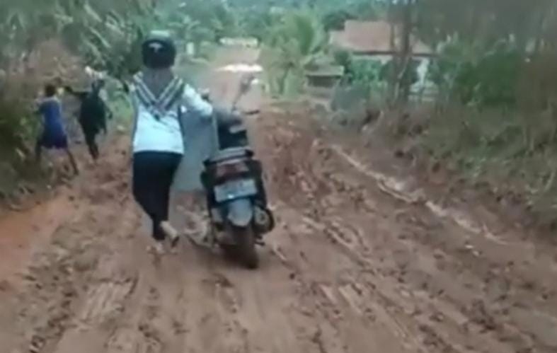Takut Jatuh Seorang Wanita Dorong Motor Saat Melintasi Jalan Berlumpur Di Desa Lebung, Banyuasin, Sumsel